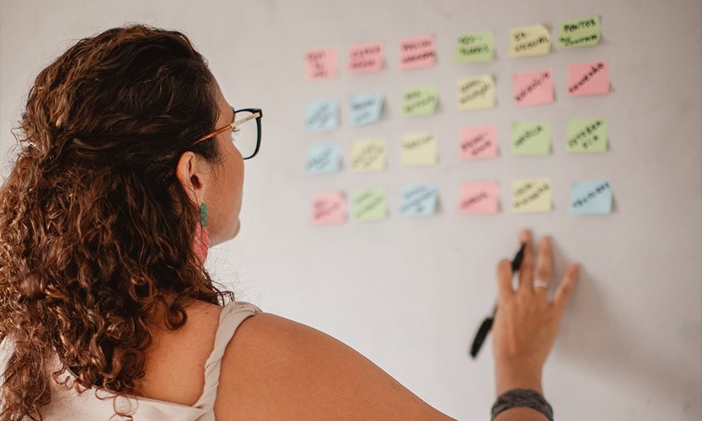 Dayse organizando post-its numa parede durante uma sessão de estratégia