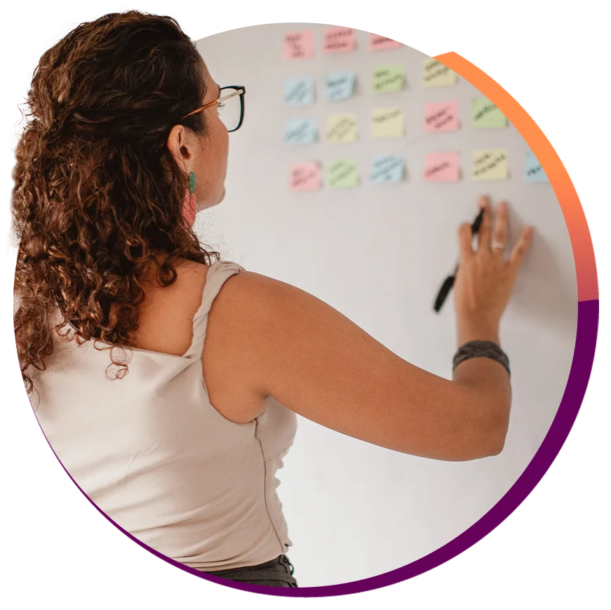 Mulher organizando post-its coloridos numa parede durante uma sessão de estratégia